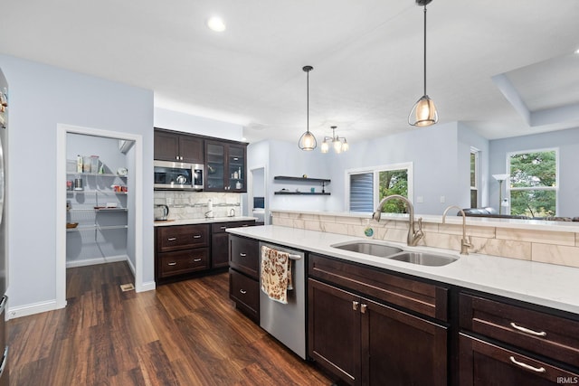 kitchen with pendant lighting, sink, stainless steel appliances, dark brown cabinetry, and dark hardwood / wood-style flooring