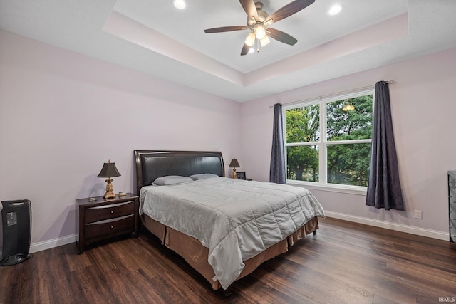 bedroom featuring a tray ceiling, ceiling fan, and dark wood-type flooring