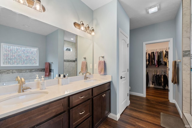 bathroom featuring wood-type flooring, vanity, a tile shower, and a textured ceiling