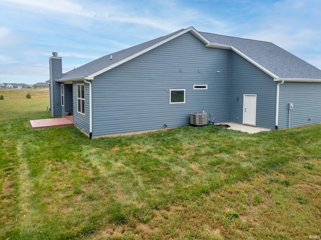 rear view of property featuring a yard, central AC unit, and a patio area