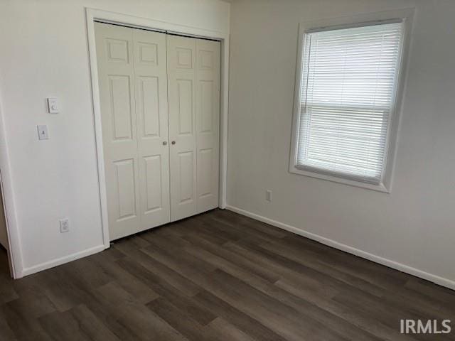 unfurnished bedroom with dark wood-type flooring and a closet