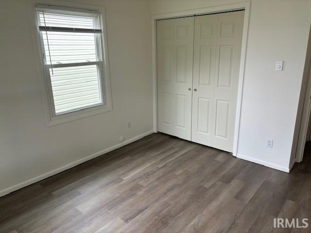 unfurnished bedroom featuring dark hardwood / wood-style flooring and a closet