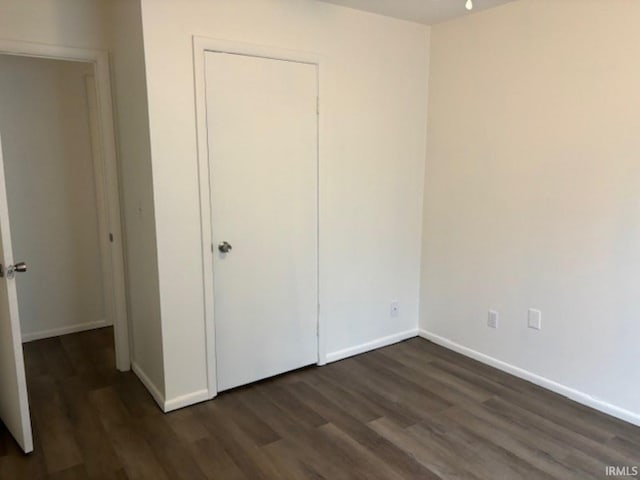 unfurnished bedroom featuring dark hardwood / wood-style flooring and a closet