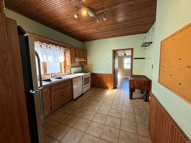 kitchen featuring white range, wood walls, plenty of natural light, and sink