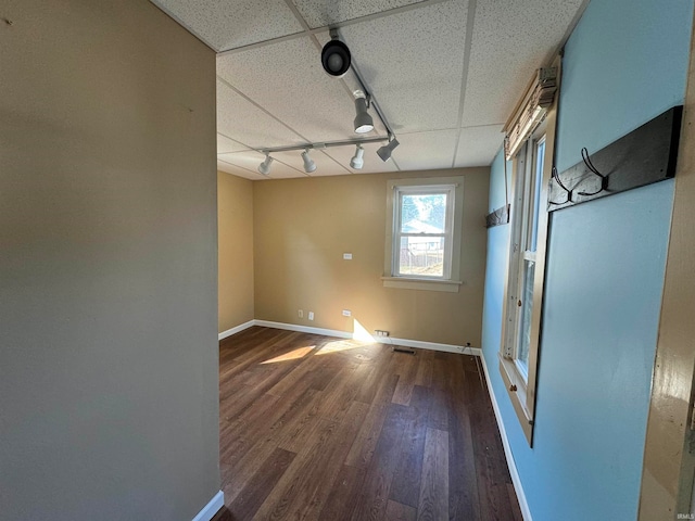 spare room with dark hardwood / wood-style floors, track lighting, and a paneled ceiling