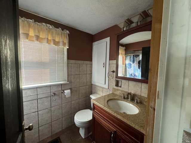 bathroom with tile walls, vanity, a textured ceiling, tile patterned flooring, and toilet