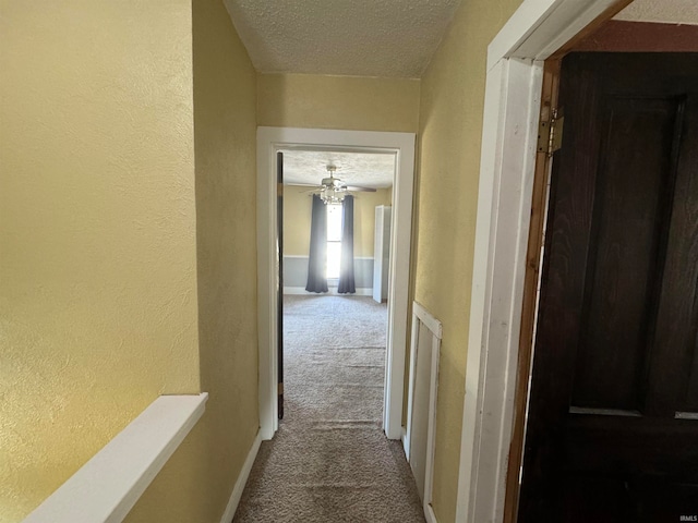 hall featuring a textured ceiling and carpet floors