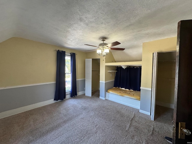 unfurnished bedroom featuring carpet, vaulted ceiling, ceiling fan, and a textured ceiling