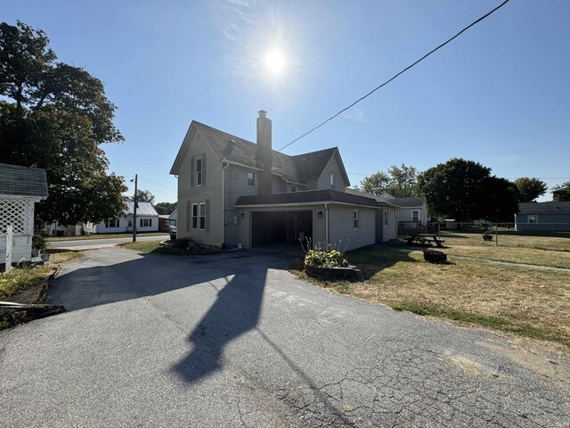 232 S Main St, Avilla, IN 46710 - view of property exterior featuring driveway, a chimney, and a yard