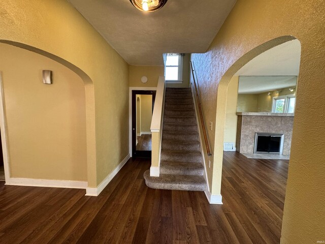 232 S Main St, Avilla, IN 46710 - stairway featuring a tile fireplace, baseboards, wood finished floors, arched walkways, and a textured wall