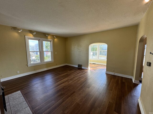 232 S Main St, Avilla, IN 46710 - unfurnished room featuring dark wood-style flooring, baseboards, a textured ceiling, arched walkways, and visible vents