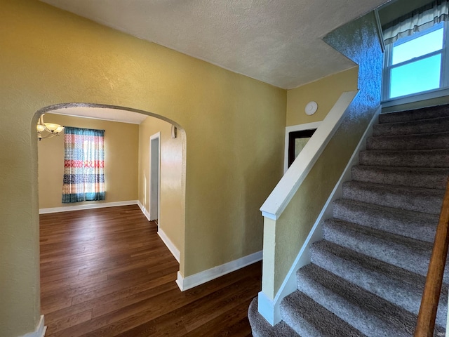 stairs featuring a textured ceiling and hardwood / wood-style flooring