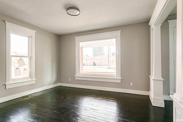 spare room with dark hardwood / wood-style floors and ornate columns