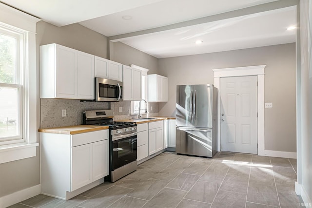 kitchen with white cabinets, stainless steel appliances, sink, and decorative backsplash