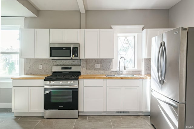 kitchen with white cabinets, appliances with stainless steel finishes, and a wealth of natural light