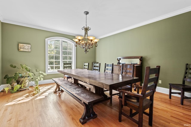 dining space with a notable chandelier, light wood-type flooring, and ornamental molding