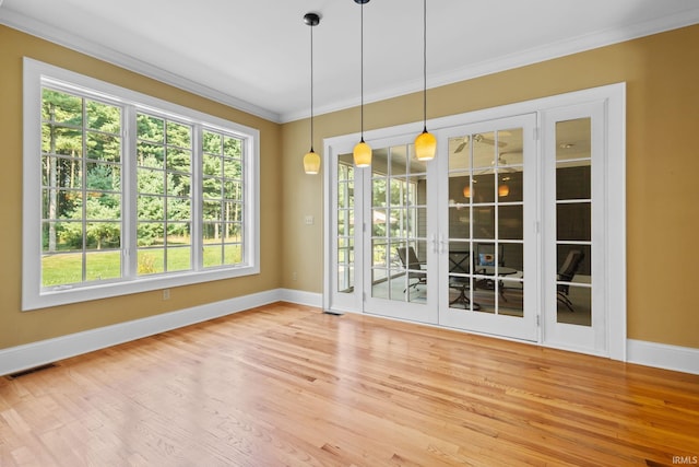 spare room featuring wood-type flooring, ornamental molding, and plenty of natural light