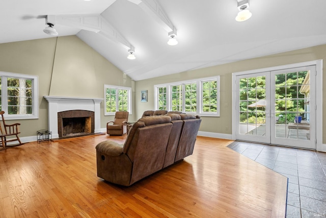 living room featuring light wood-type flooring, a tiled fireplace, and high vaulted ceiling