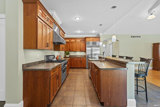 kitchen with hanging light fixtures, a breakfast bar, high quality appliances, ornamental molding, and wall chimney range hood