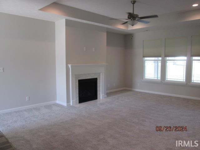 unfurnished living room featuring ceiling fan and light colored carpet