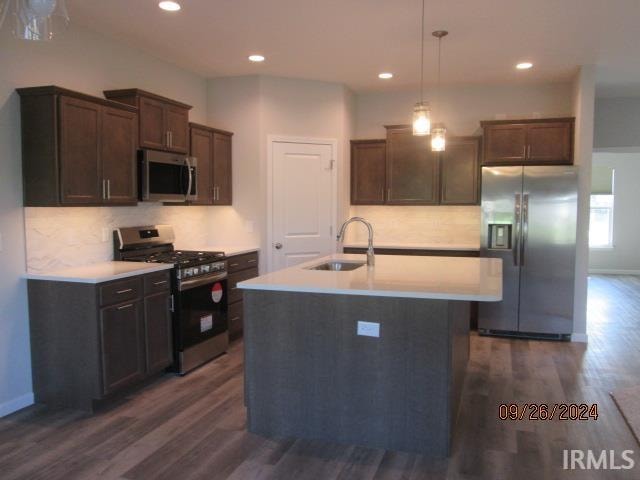 kitchen featuring dark hardwood / wood-style floors, sink, stainless steel appliances, and decorative light fixtures