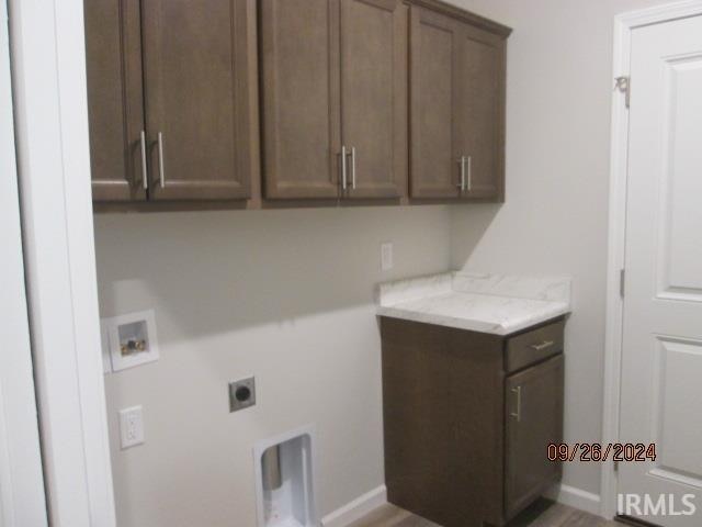 clothes washing area with cabinets, electric dryer hookup, and washer hookup