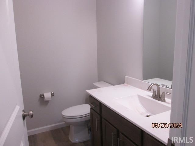 bathroom with wood-type flooring, vanity, and toilet