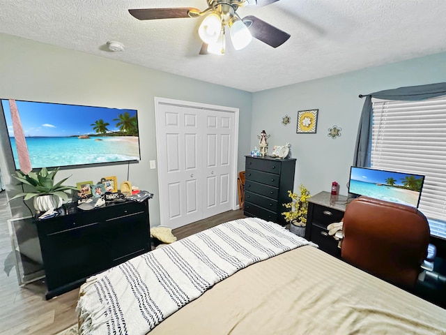 bedroom featuring a closet, ceiling fan, wood-type flooring, and a textured ceiling