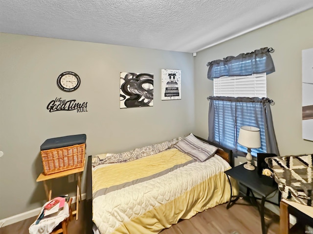 bedroom with a textured ceiling and wood-type flooring