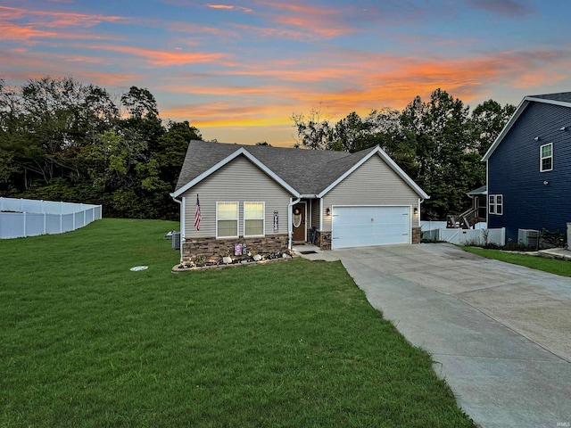 view of front of property featuring a garage, a lawn, and central AC