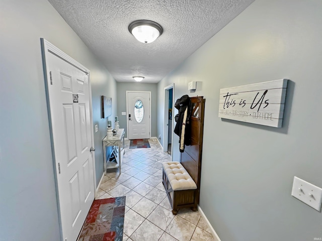 hallway with a textured ceiling and light tile patterned floors