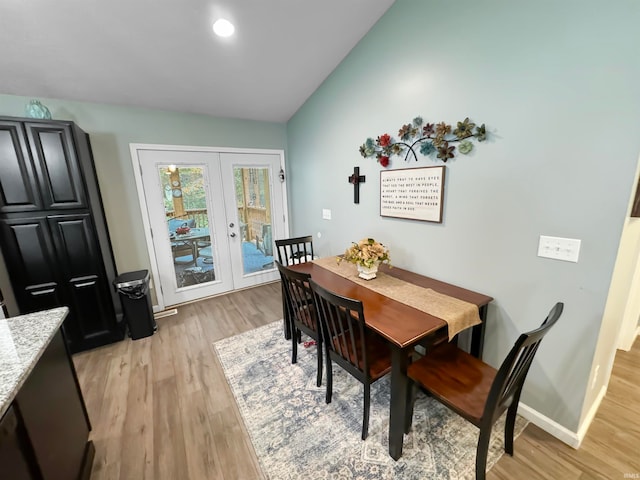 dining room with vaulted ceiling, light hardwood / wood-style floors, and french doors