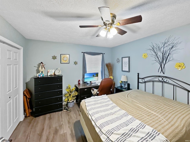 bedroom featuring light hardwood / wood-style flooring, a closet, ceiling fan, and a textured ceiling