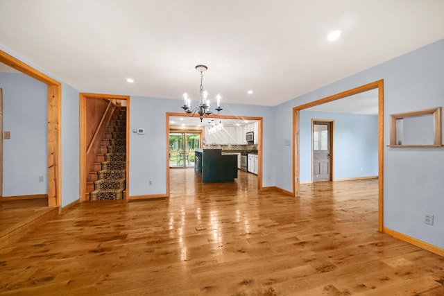 unfurnished dining area featuring wood-type flooring and a notable chandelier