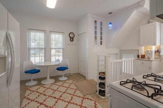 kitchen featuring crown molding, white cabinetry, pendant lighting, and white appliances