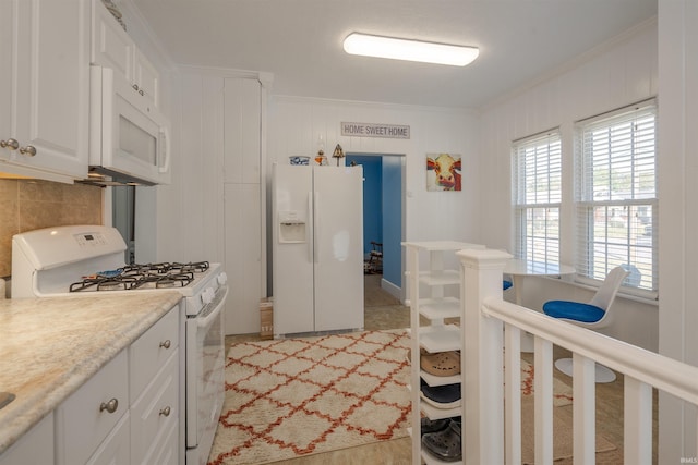 kitchen featuring white appliances, ornamental molding, and white cabinets