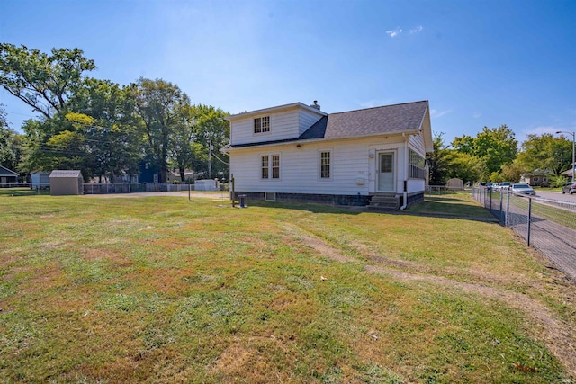 rear view of property featuring a storage shed and a lawn