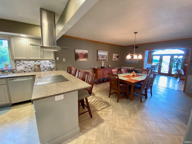 kitchen featuring tasteful backsplash, stainless steel dishwasher, island range hood, french doors, and decorative light fixtures