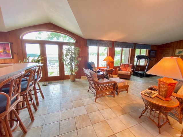 living room with french doors, wooden walls, lofted ceiling, and plenty of natural light