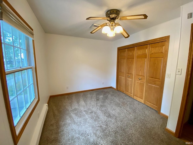 unfurnished bedroom with dark colored carpet, ceiling fan, and a closet