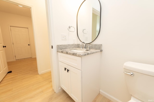 bathroom with wood-type flooring, vanity, and toilet