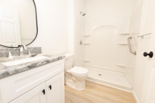 bathroom featuring walk in shower, hardwood / wood-style flooring, vanity, and toilet