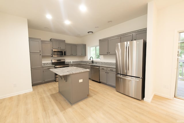 kitchen featuring gray cabinetry, appliances with stainless steel finishes, sink, a kitchen island, and light hardwood / wood-style flooring