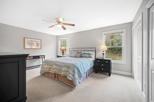 carpeted bedroom with ceiling fan, a closet, and multiple windows