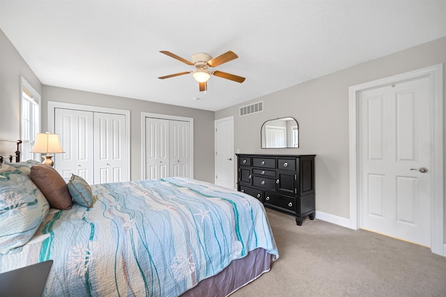 bedroom with carpet, two closets, and ceiling fan