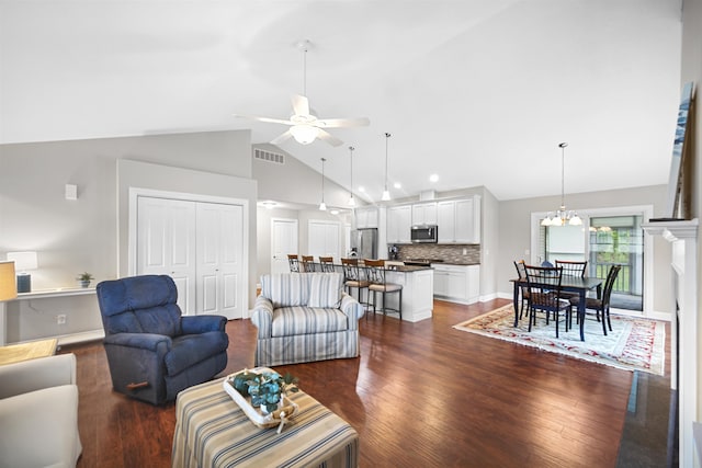 living room with ceiling fan with notable chandelier, dark hardwood / wood-style flooring, and high vaulted ceiling