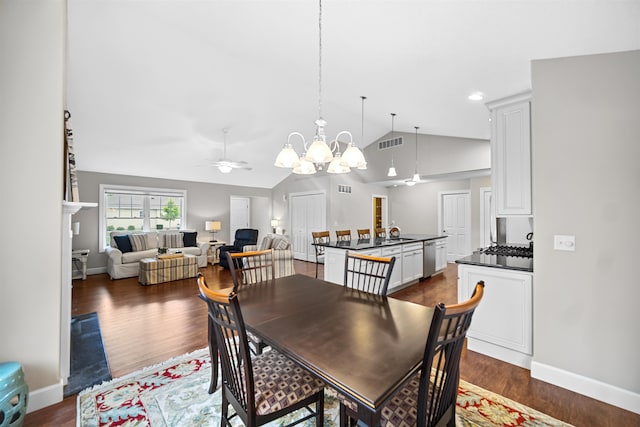 dining area featuring ceiling fan with notable chandelier, vaulted ceiling, sink, and dark wood-type flooring