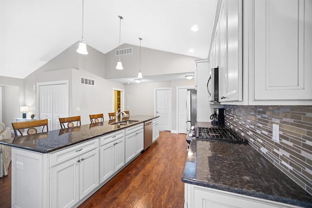 kitchen with pendant lighting, dark hardwood / wood-style floors, a kitchen island with sink, white cabinetry, and appliances with stainless steel finishes