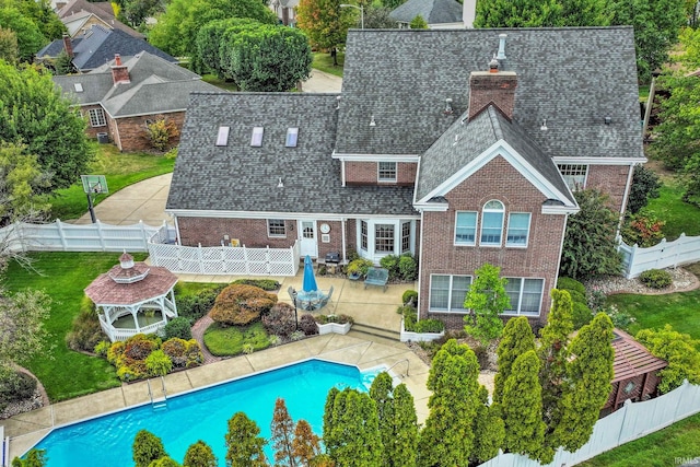 rear view of house with a fenced in pool, a yard, and a patio