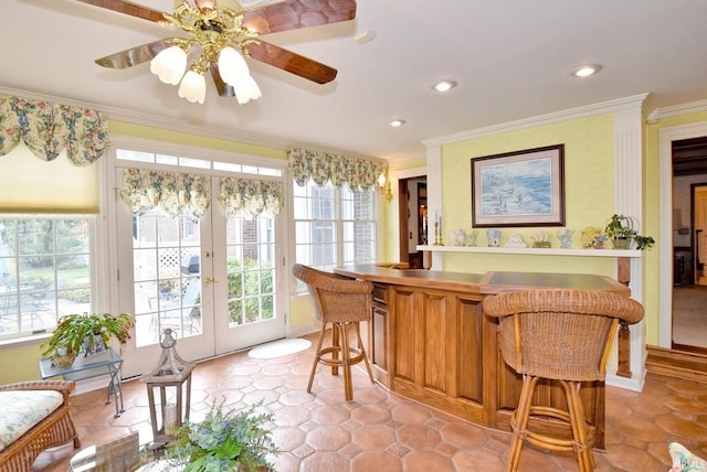 interior space featuring a kitchen bar, ornamental molding, ceiling fan, and kitchen peninsula